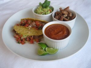 Carnitas (lombo desfiado), salsa de legumes assados, guacamole, pico de gallo e tortillas mexicanas.